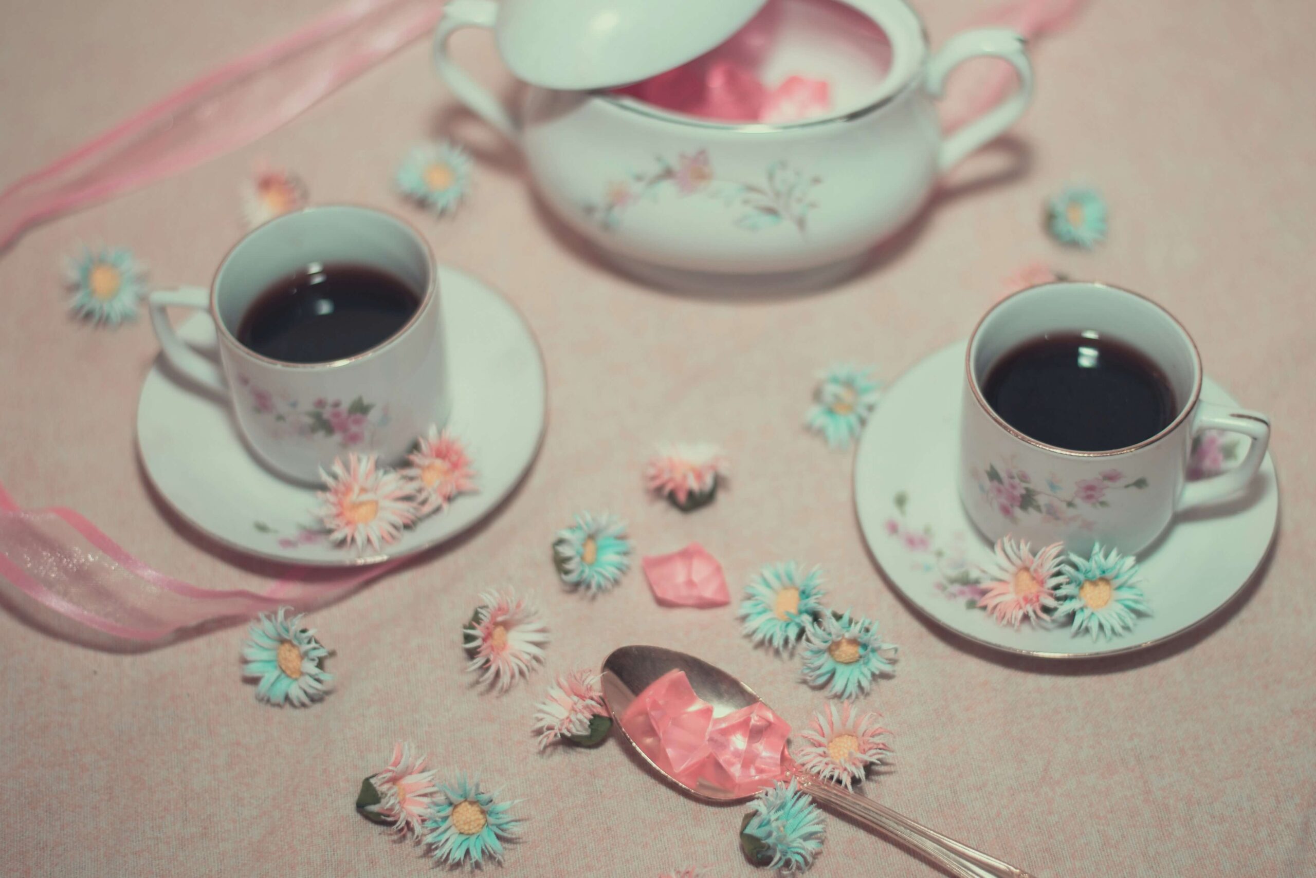 White tea set on a pink table cloth with flowers.