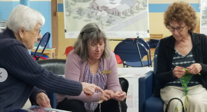 knitting Picture of two women at a Yarn & Stitch program teaching Director Bartoli to knit.
